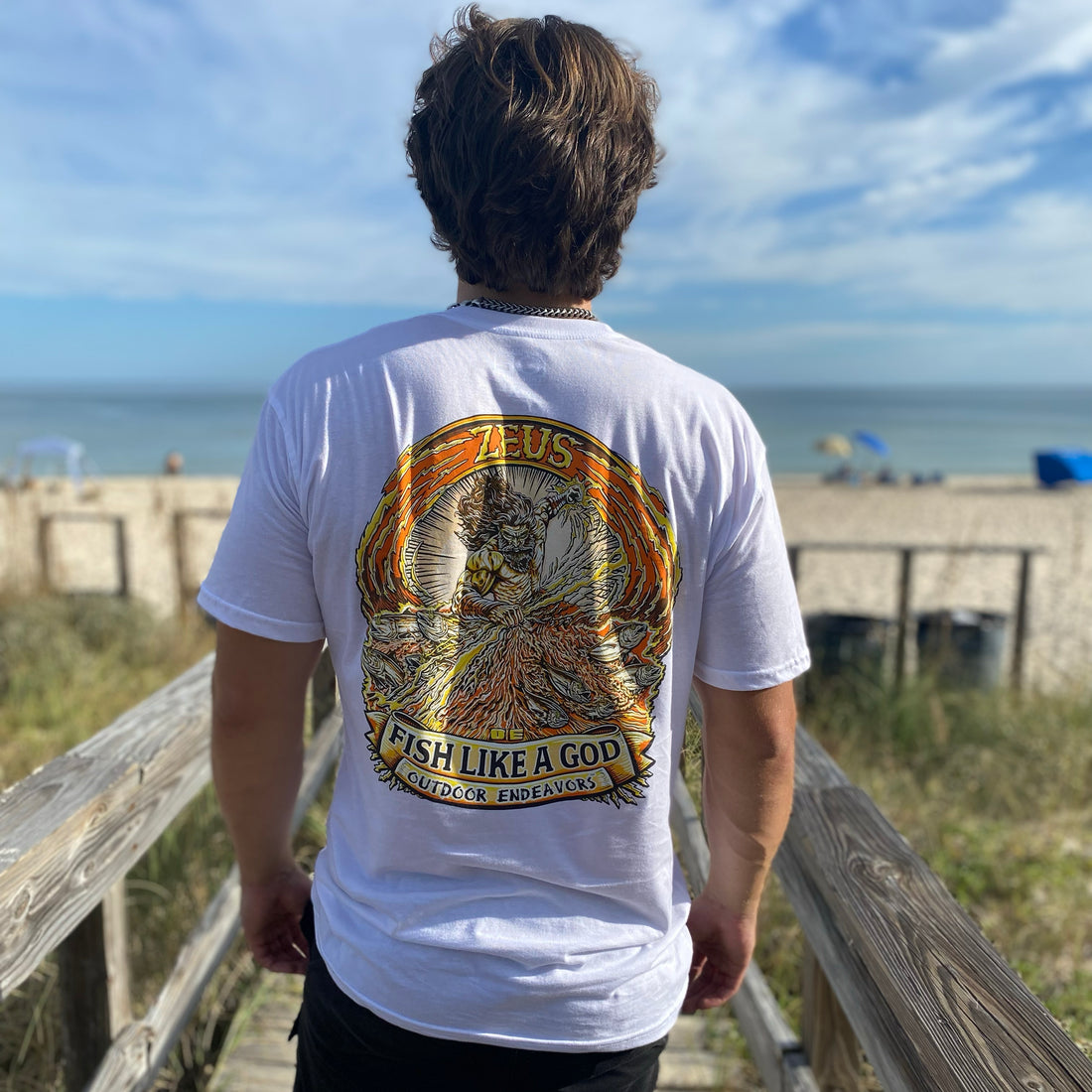 White t-shirt with a gold and orange graphic design on the back, featuring text and a logo.